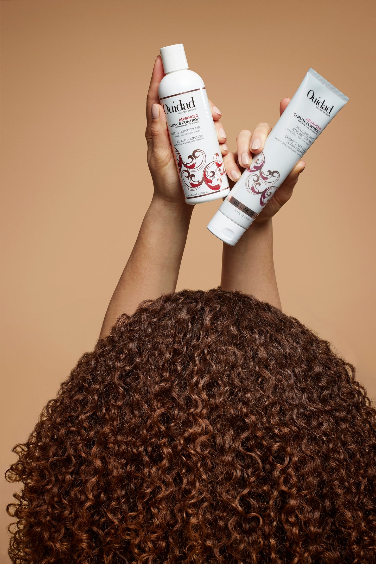 Curly haired model holding Advanced Climate Control® Heat & Humidity Gel and Styling Cream