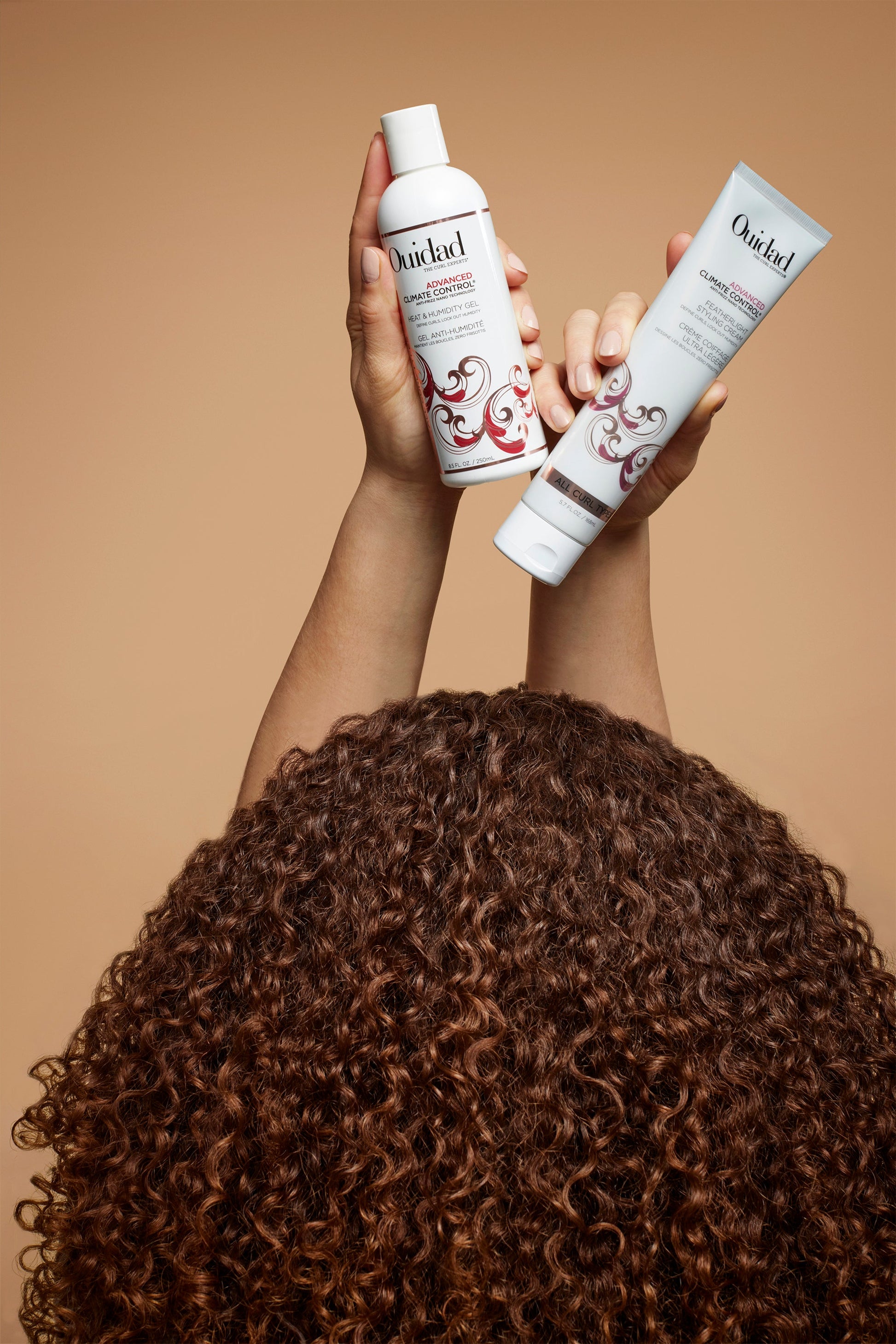 Curly haired model holding Advanced Climate Control® Heat & Humidity Gel and Styling Cream